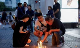 Một số người thắp nến bên ngoài trung tâm thương mại Siam Paragon sau vụ xả súng ngày 4/10. (Ảnh: Reuters)