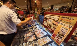 Công nhân xếp hải sản nhập khẩu từ Chile, Pháp và Canada gần tấm bảng và màn hình hướng dẫn cách nấu kiểu Nhật, tại một siêu thị Nhật Bản ở Bắc Kinh ngày 24/8. (Ảnh: AP)