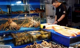 Một người bán hàng sơ chế hải sản tại quầy ở chợ hải sản Bắc Kinh, Trung Quốc, ngày 24/8. (Ảnh: Reuters)