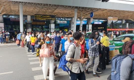 Hành khách đi bộ cắt ngang các làn ô tô trước ga quốc nội.