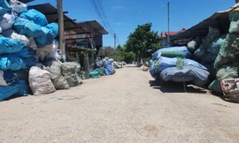 Vật liệu tái chế được người dân thu gom, phân loại xếp hai bên đường vào làng