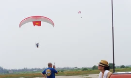 Phi công Nguyễn Tuấn Võ đang bay với lá cờ Tổ quốc. Dưới đất, anh Julien đang hướng dẫn phi công thông qua bộ đàm