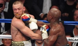 Conor McGregor (trái) dính một đòn nặng từ Mayweather.
