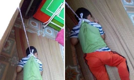 Bé trai bị buộc dây, treo người nơi cửa sổ.
