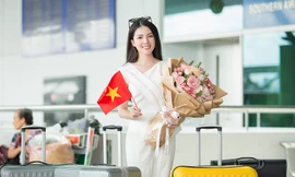 Hoa khôi Huỳnh Thúy Vi cầm hoa và cờ Việt Nam trước giờ lên máy bay.