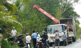 Chiếc xe tải nằm gọn dưới kênh và người dân phụ giúp chuyễn hàng lên bờ.