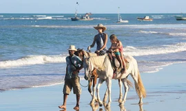 Bà mẹ hai con cùng các con cưỡi ngựa dạo trên biển.
