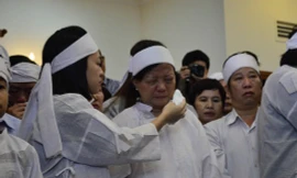 Con gái ông Nguyễn Bá Thanh lau nước mắt cho mẹ trong giờ truy điệu sáng 16/2.