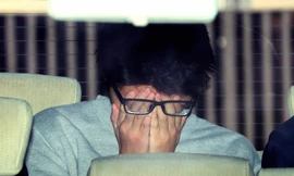 Bị cáo che mặt khi bị bắt tại đồn cảnh sát ở Tokyo. Ảnh: Ashahi Shinbum.