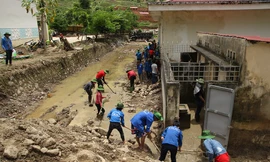 Các tình nguyện viên dọn dẹp bùn đất khu vực trường học và nhà sinh hoạt cộng đồng