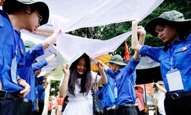 Nữ tình nguyện viên tham gia che mưa cho thí sinh rời phòng thi. Ảnh: Như Ý