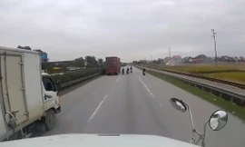 Các thanh niên đi xe máy không đội mũ đánh võng trước mặt container