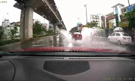 Chiếc sedan lao nhanh trên đường mưa, bắn nước lên người đi xe máy