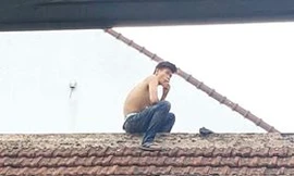 Nam thanh niên nghi ngáo đá đột nhiên leo mái nhà, liên tục la hét, dọa đâm bụng mình. Ảnh: Dân Việt