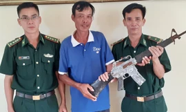 Khẩu súng quân dụng do ngư dân Nguyễn Hậu Nghĩa (giữa) phát hiện trong lúc đánh cá vùng cửa biển.