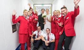 Cô dâu, chú rể tươi cười chụp ảnh cùng các tiếp viên hàng không trên máy bay