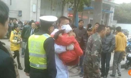 Các nhân viên y tế đưa một em nhỏ bị thương ở đầu lên xe cấp cứu.