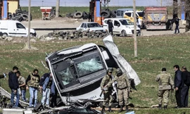 Các binh sỹ đi qua một chiếc xe bị hư hại ở Lice, tỉnh Diyarbakir, Thổ Nhĩ Kỳ sau vụ đánh bom khiến 6 người chết hôm 18/2