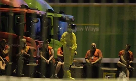 Một nhân viên của đội phá bom và chất độc hóa học trong trang phục bảo hộ bên ngoài văn phòng phân loại bưu kiện Stokke.