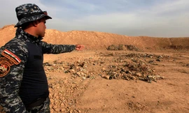 Một binh sỹ Iraq chỉ vào ngôi mộ tập thể ở thị trấn Hammam al-Alil hôm 9/11.
