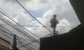 Nam thanh niên ngồi chồm hổm trên ngọn trụ điện.