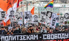 Người biểu tình giơ cao chân dung của những người bị giam và tấm biểu ngữ. 