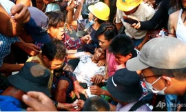 Đám đông vây quanh một người biểu tình bị thương ở Hlaing Tharyar ngày 14/3. (Ảnh: AP)