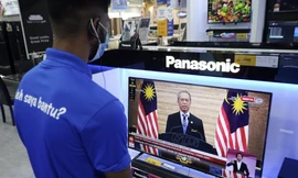 Nhân viên một cửa hàng điện tử ở Kuala Lumpur xem Thủ tướng Muhyiddin phát biểu trên truyền hình ngày 12/1. (Ảnh: AP)