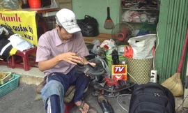 Anh Bình đang sửa giày cho một người bán vé số