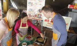 “Cô giáo” phố Hội chỉ dẫn hai học trò cách chiên bánh xèo. Ảnh: Thanh Trần.