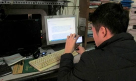 Một sinh viên đang thực hiện công đoạn sao chép kiến thức trong quán phô-tô bằng điện thoại. Ảnh: Nguyễn Hoan