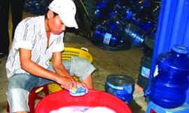 Xúc rửa bình qua loa bằng nước rửa bát. Ảnh: Lê Nguyễn