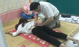 Ông Long kiểm tra cho một thiếu nữ trong “phòng kỹ thuật” luộm thuộm, nhếch nhác. Ảnh: T.T