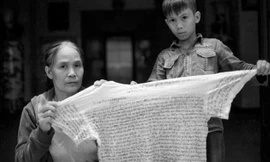 Bà Việt (mẹ Mạnh) cùng đứa con của Lê Văn Mạnh cầm lá thư viết trên áo của Mạnh gửi trong tù ra.