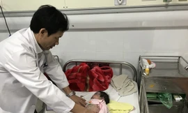 Bác sĩ Đỗ Thiện Hải khám cho bệnh nhi G.B. Ảnh: T.Hà.