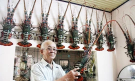 Ông Nguyễn Minh Châu và những con tôm hùm tre do ông chế tác. Ảnh: H. Văn
