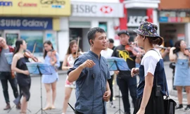 Lưu Quang Minh đang chỉ đạo dàn nhạc biểu diễn trên phố đi bộ Hà Nội.