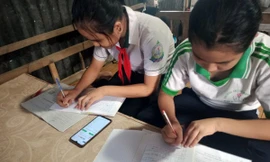 Hai học sinh học trực tuyến chung bằng một chiếc điện thoại