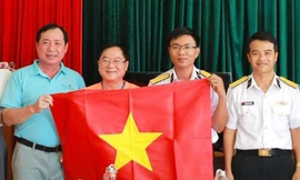 Nhà báo Lê Xuân Sơn, ông Tiết Văn Thành và ông Nguyễn Viết Vy - Bí thư huyện ủy Lý Sơn tặng cờ Đồn Biên phòng đảo Lý Sơn. Ảnh: Trọng Tài