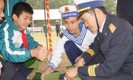 Cán bộ, chiến sĩ Lữ đoàn Hải quân đánh bộ 147 và các em học sinh cùng gói bánh chưng tặng người nghèo đón Tết. Ảnh: Nguyễn Minh.