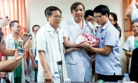 PGS.TS Vũ Bá Quyết, Giám đốc BV Phụ sản T.Ư trao bé Gấu cho người cha.