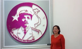 Bà Thục bên bức tranh ghép bằng diêm chân dung Đại tướng Nguyễn Chí Thanh. Ảnh: Trung Dũng.