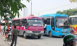 Xe khách dàn hàng ngang bắt khách trên đường nhưng một cán bộ công an (vòng tròn) làm việc tại cổng bến Giáp Bát sáng 20/8 chỉ đứng nhìn.