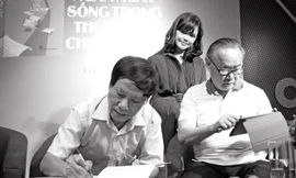 Vũ Công Chiến ký tặng sách trong buổi ra mắt “Hồi ức lính” năm ngoái. Bên cạnh là vợ anh và nhà văn Ngô Thảo. Ảnh: Nguyễn Đình Toán.