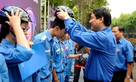 Bí thư Thứ nhất T.Ư Đoàn Nguyễn Đắc Vinh tặng mũ bảo hiểm đạt chuẩn cho tình nguyện viên đội phản ứng nhanh giao thông của Thành Đoàn Hà Nội. Ảnh: Xuân Tùng.