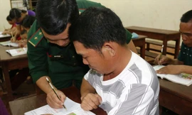 Trung úy Trần Thế Mạnh hướng dẫn học viên viết chữ trong một buổi học. Ảnh: B.S.