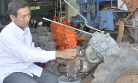 “Kỹ sư chân đất” Phạm Thanh Liêm đang lắp máy. Ảnh: Hòa Hội.