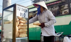 Một người mua ve chai đang lấy bánh mì từ thiện.