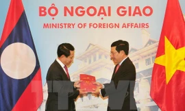 Phó Thủ tướng, Bộ trưởng Ngoại giao Phạm Bình Minh và Bộ trưởng Ngoại giao Lào Saleumxay Kommasith trao đổi tượng trưng hai ấn phẩm văn kiên pháp lý biên giới Việt Nam-Lào. (Ảnh: Nguyễn Khang/TTXVN)