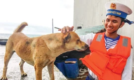 Chiến sĩ Não Xuân Long chia tay chú chó Bin bên cầu cảng đảo Tiên Nữ Ảnh: Trường Phong.